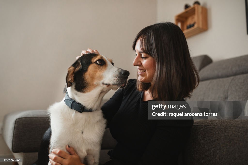 Caucasian adult woman with her dog at home hugging