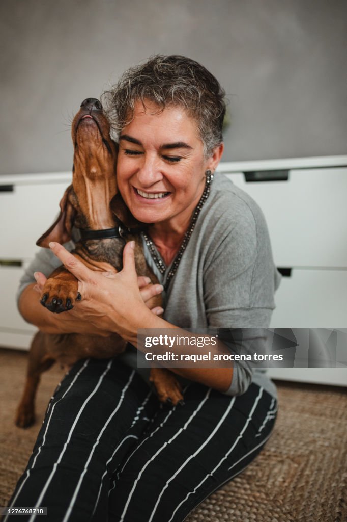 Caucasian adult woman with her dog at home hugging