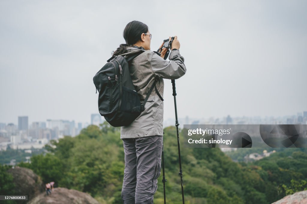 Asia girl hiking in city park and take photo with smartphone