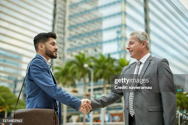 hispanic businessmen shaking hands in downtown miami - miami business stock pictures, royalty-free photos & images