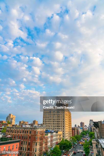 spring clouds float over the east village buildings at new york city. - east village stock pictures, royalty-free photos & images