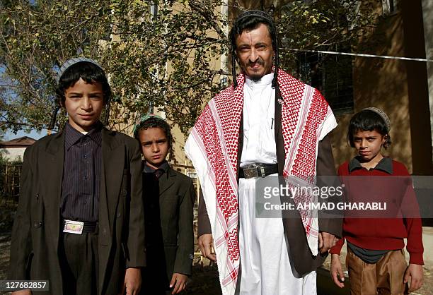 Yemeni Jewish Rabbi Yahia Yussef Mussa , sporting a chequerred Keffiya, poses for a picture with unidentified young relatives outside his apartment...