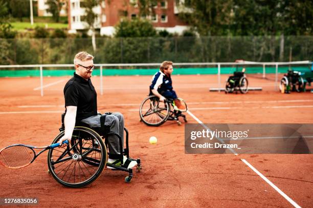 männer im rollstuhl spielen tennis im freien - rollstuhltennis stock-fotos und bilder