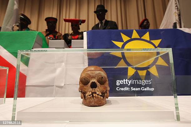 Members of a delegation from Namibia stand over 20 skulls, many of them in boxes draped under Namibian flags, at the conclusion of a ceremony at...