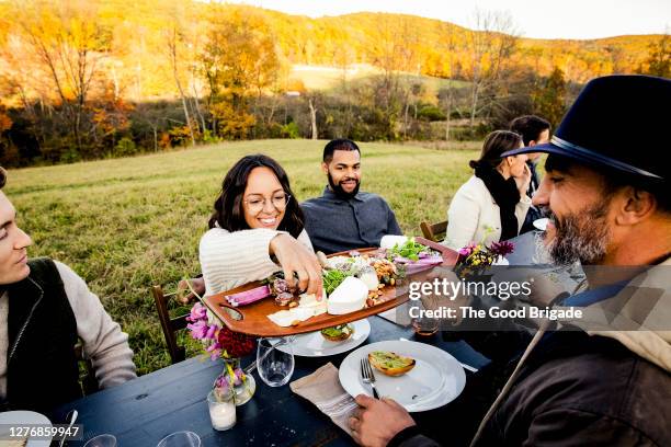 friends sharing food during outdoor dinner party - käseplatte stock-fotos und bilder