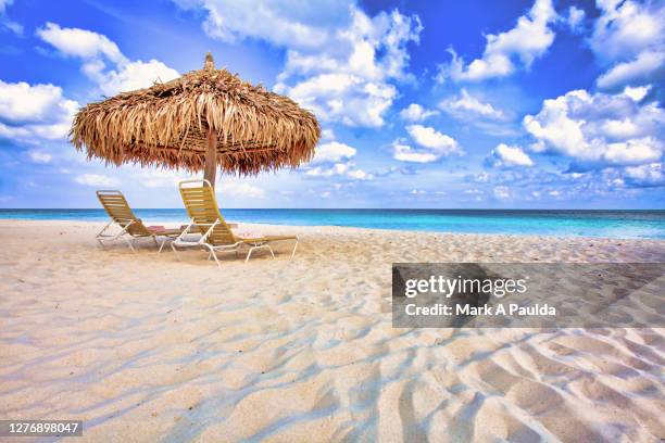 two lounge chairs and beach umbrella on a white sandy beach in aruba - aruba photos et images de collection