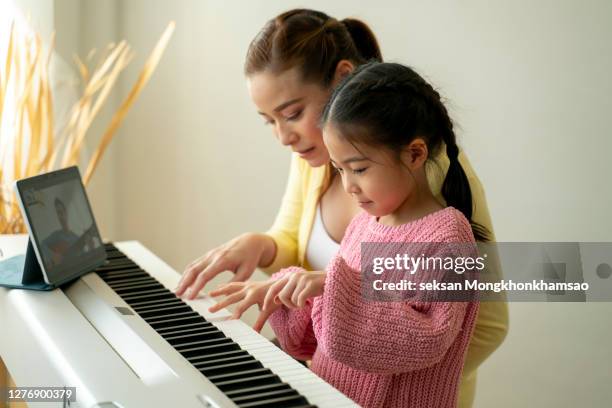 happy little asian deaughter playing piano with mother at home, mother teaching daughter to play piano,they play and sing songs. they are having fun. - keyboard musical instrument child stock pictures, royalty-free photos & images