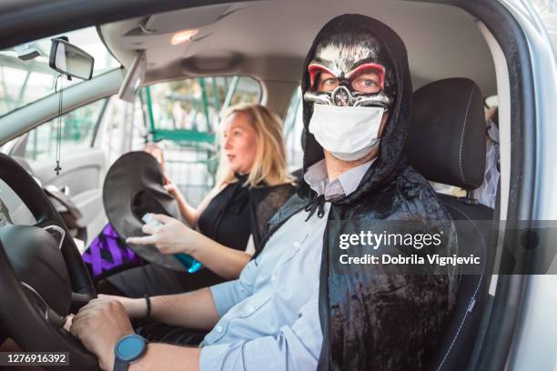 man waring halloween costume and protective mask driving a car - halloween covid stock pictures, royalty-free photos & images