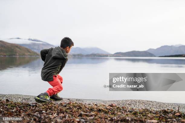 kid skipping stones in lake. - throwing water stock pictures, royalty-free photos & images