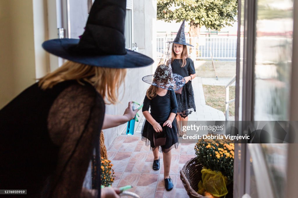 Happy children in Halloween witch costumes having their hands sanitized