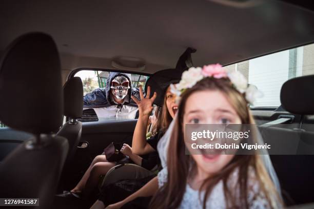 glückliche kinder fahren in einem auto mit ihrem vater, alle tragen halloween-kostüme - screaming happy in car stock-fotos und bilder