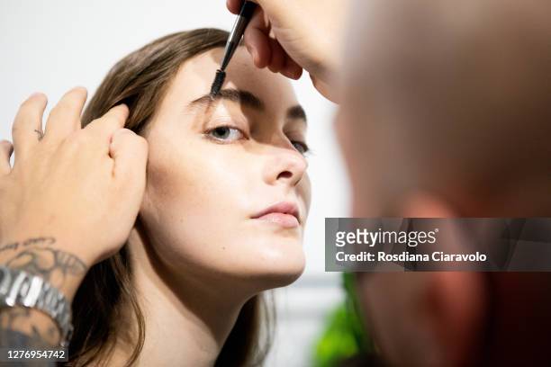 Make up artist does the final touch of gel eyebrow during the line up before the show is seen backstage at the Shi.Rt fashion show during the Milan...
