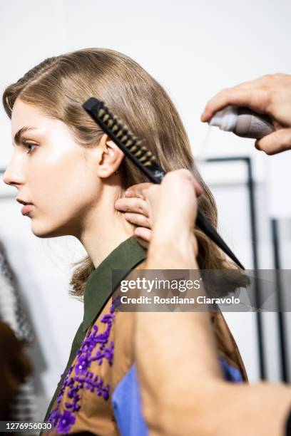 An Hairstylist, hair detail, does the final touch during the line up before the show is seen backstage at the Shi.Rt fashion show during the Milan...