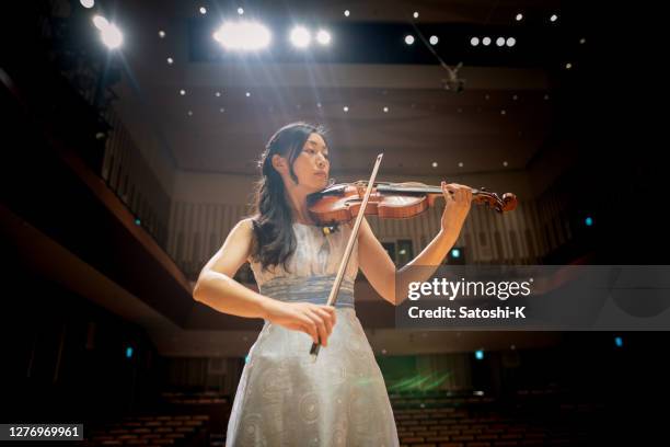 コンサートホールでバイオリンを演奏する女性バイオリニスト - violin ストックフォトと画像