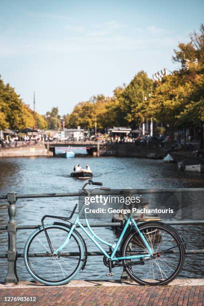 blue bicycle on a bridge in amsterdam, holland - amstel stock pictures, royalty-free photos & images