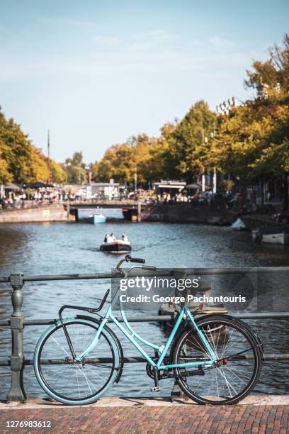 blue bicycle on a bridge in amsterdam, holland - amsterdam cycling stock pictures, royalty-free photos & images