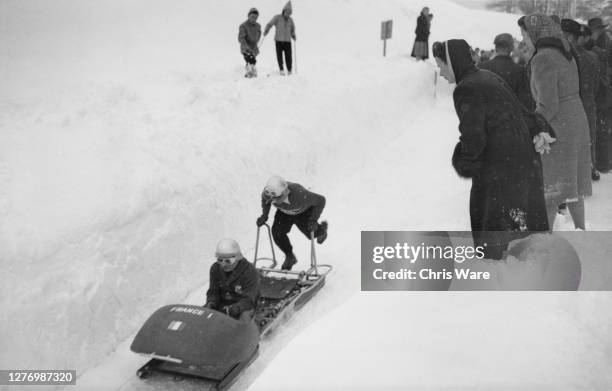 Spectators watch as the France two-man bobsleigh begin a trial run ahead of the two-man bobsleigh event of the 1948 Winter Olympics, at St...