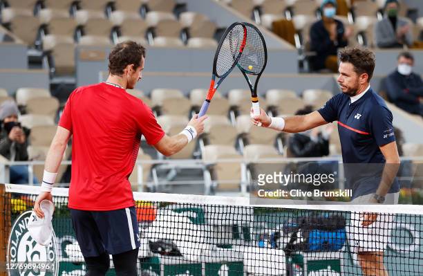 Stan Wawrinka of Switzerland knocks racquets with Andy Murray of Great Britain as part of COVID-19 precautions following victory in his Men's Singles...