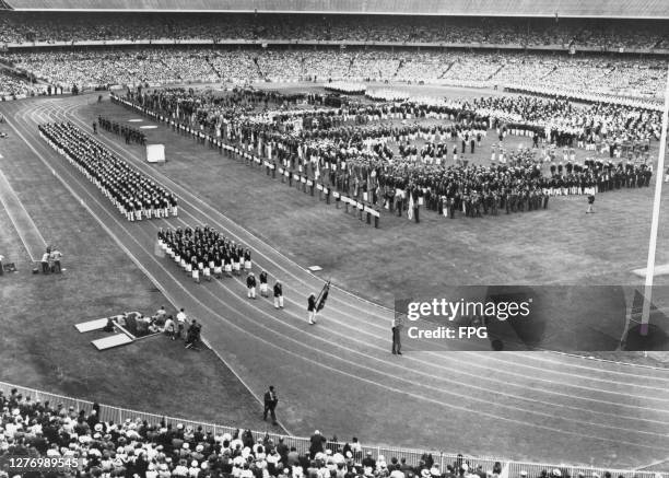 High angle view as one of the competing nations walk the track, following the flagbearer at the opening ceremony at the 1956 Summer Olympics, at...