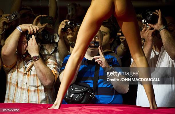 Fairgoers take pictures and shoot videos as a showgirl performs at a stand at the 15th Venus international Erotic and Lifestyle trade fair in Berlin...