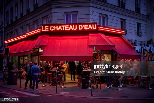 Parisians drink outside at a bar the night before restrictions come into place forcing bars and cafes in the capital to close early on September 27,...