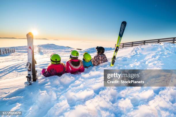 family lying down on the snow - family skiing stock pictures, royalty-free photos & images