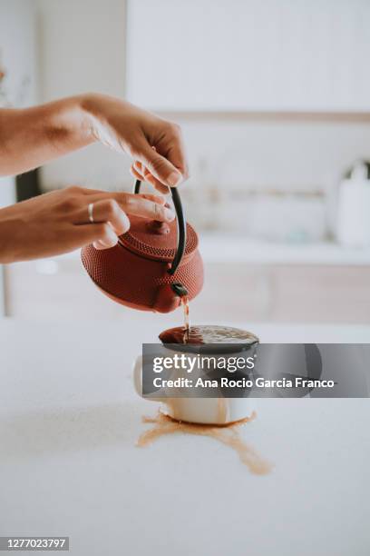 a young woman serving tea and overflowing the mug - steep stock pictures, royalty-free photos & images