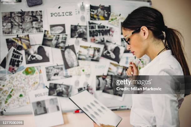 the lady detective is looking for clues about the case of a serious crime - - the hard work of a detective in the office - the detective in the office is working to gather evidence and clues in finding the killer - detective stock pictures, royalty-free photos & images