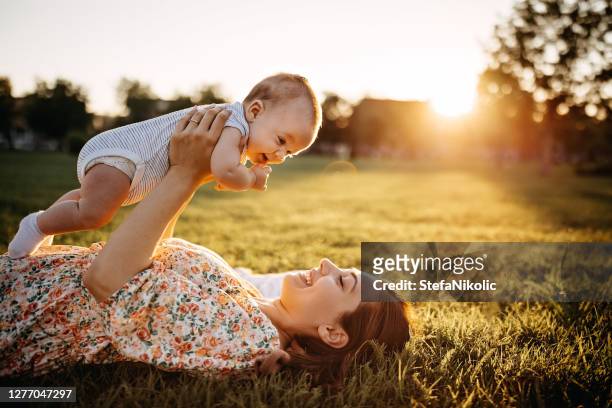 madre y bebé acostados en el prado - baby nature fotografías e imágenes de stock