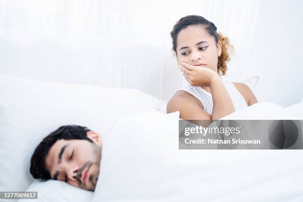 angry young woman with man sleeping in bed. - suspicion infidelity stock pictures, royalty-free photos & images