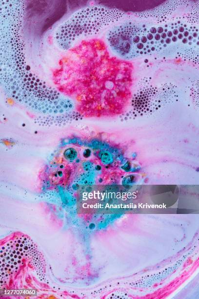 pink and blue bath bomb dissolving in the water. - bath bomb stock pictures, royalty-free photos & images