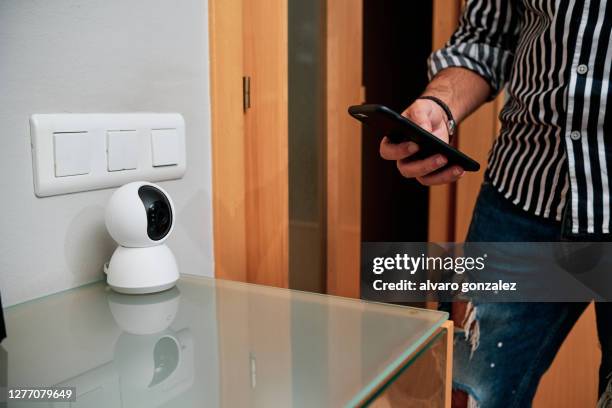a man hands using smartphone to manipulate a camera - home security camera stock pictures, royalty-free photos & images
