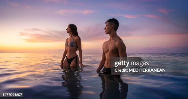 junges paar am strand mit blick auf den sonnenuntergang im meer - girl beach sunset stock-fotos und bilder