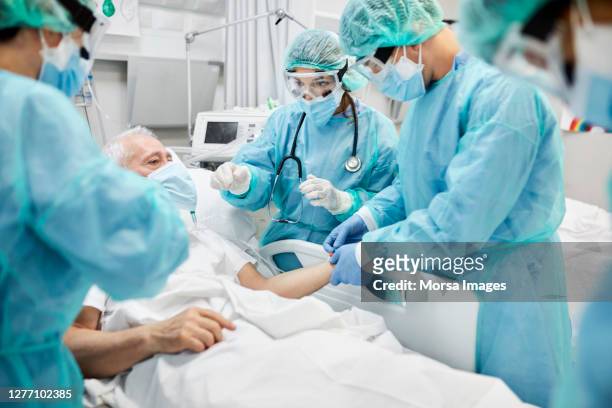 doctors examining coronavirus patient in ward - icu ward stock pictures, royalty-free photos & images