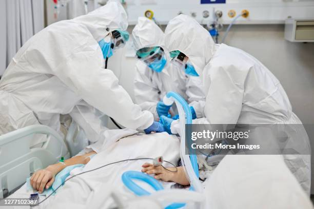 covid-19中の若い患者の酸素マスクを調節する医師 - hospital ventilator ストックフォトと画像