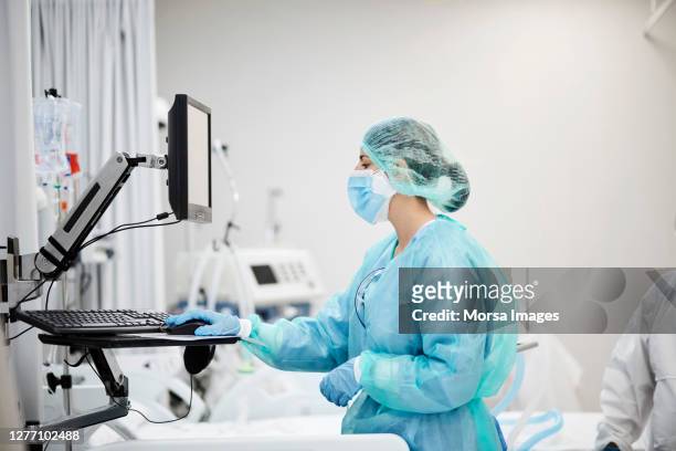 nurse using computer in covid-19 ward - intensive care unit stock pictures, royalty-free photos & images