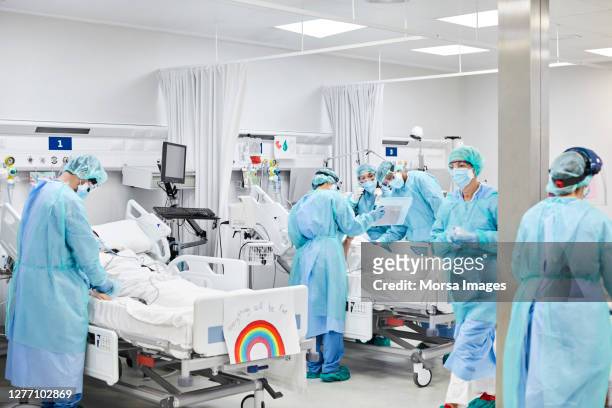mediziner, die während der pandemie auf patienten einarbeiten - intensivstation stock-fotos und bilder