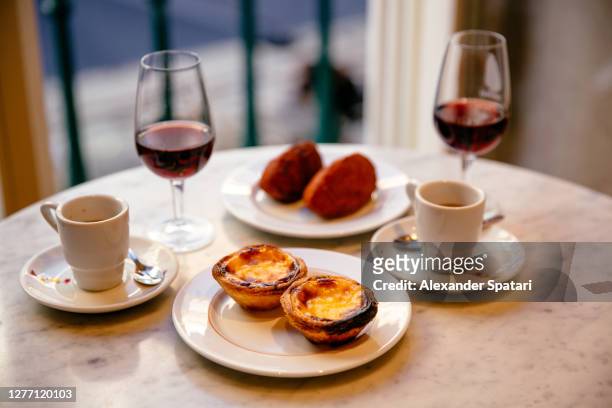 pasteis de nata and pasteis de bacalhau served with port wine and espresso coffee - port stockfoto's en -beelden