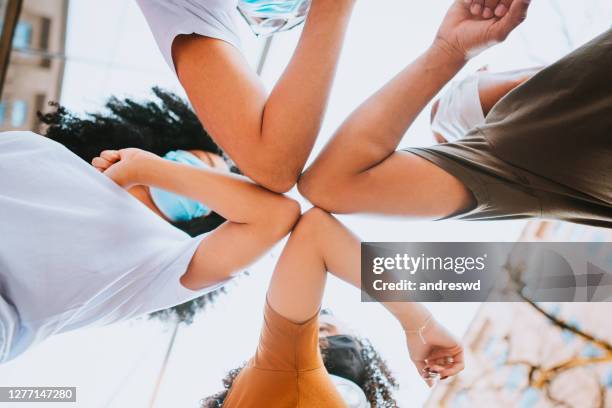 young friends wearing face mask doing new social distancing greet with elbows bumps for preventing coronavirus spread - touching elbows stock pictures, royalty-free photos & images