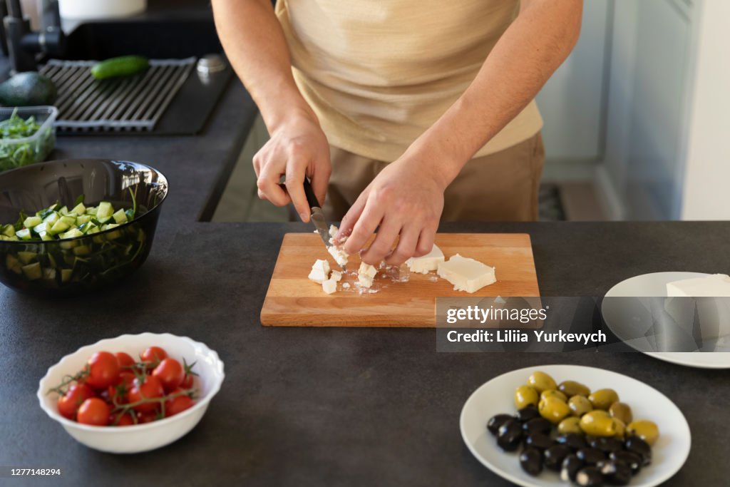 A young man prepares a vegetable salad in his kitchen.