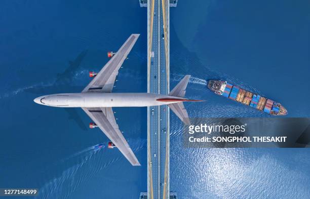 passenger planes that fly over bridges with cars and traffic and carry cargo ships sailing in the river. transportation and business rebuilding after the coronavirus outbreak or covid-19 that caused the global economy to be hit hard - cargo ships stockfoto's en -beelden