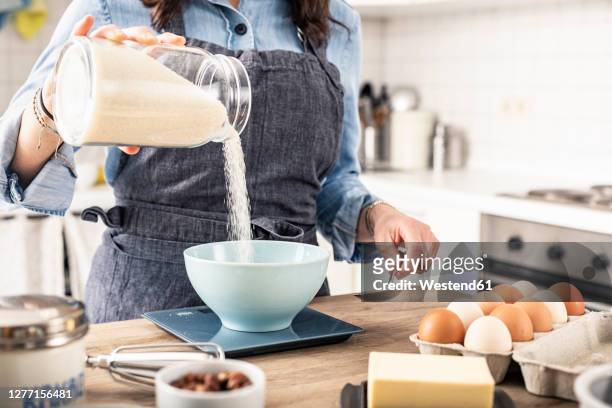 woman weighing flour on kitchen scale for making cake at home - köksvåg bildbanksfoton och bilder