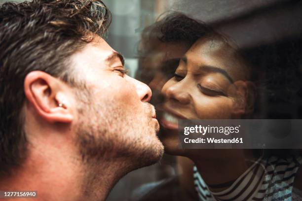 close-up of romantic man kissing girlfriend through glass window - kissing mouth stock pictures, royalty-free photos & images