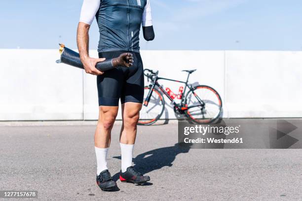 male athlete holding artificial hand while standing on road during sunny day - legs in stockings stock pictures, royalty-free photos & images