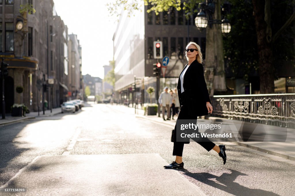 Fashionable businesswoman crossing street in city