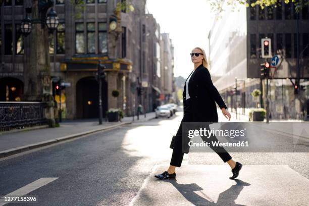 fashionable female professional crossing street in city - business woman walking stock pictures, royalty-free photos & images