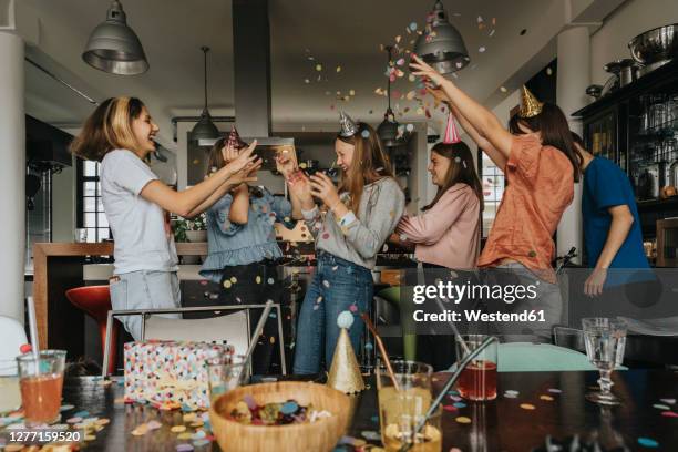 cheerful friends throwing confetti on birthday girl while celebrating at home - 12 13 jahre mädchen stock-fotos und bilder