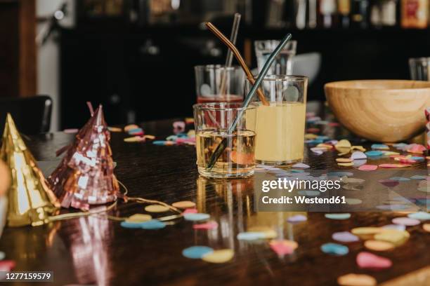 close-up of drinks with party hats and confetti on dining table at home - home party ストックフォトと画像