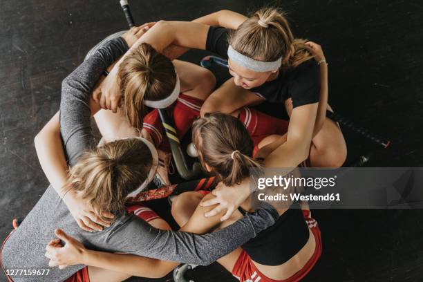 hockey players huddling while crouching on floor in health club - huddling stock-fotos und bilder