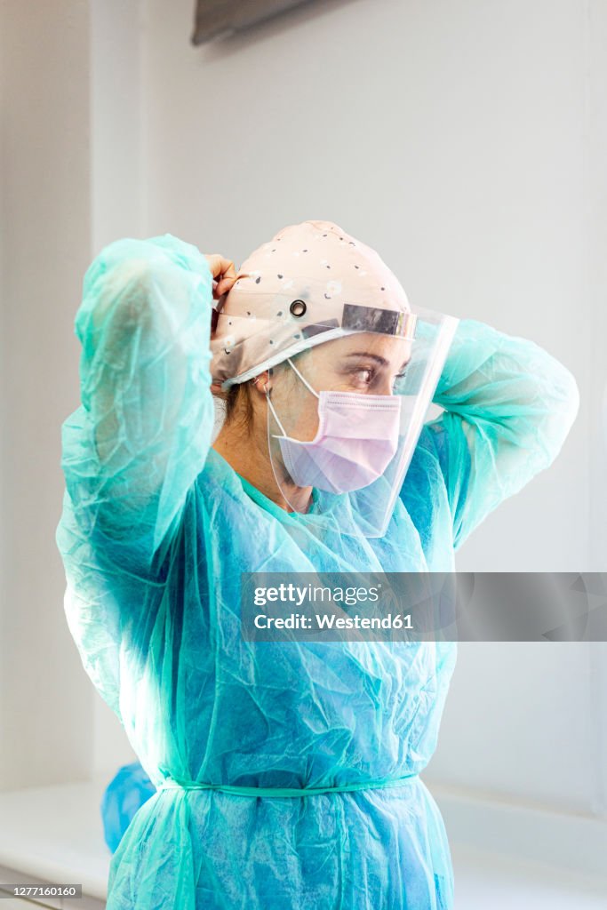 Doctor in protective suit wearing face shield while standing at clinic